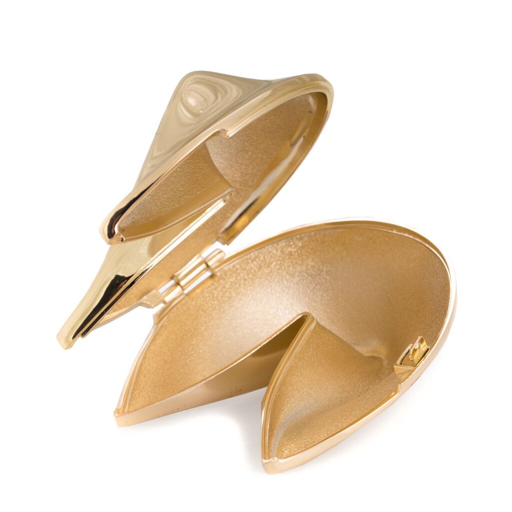 A large, gold fortune cookie box with a clasp to close and open, representing items that are perfect for gift-giving. 