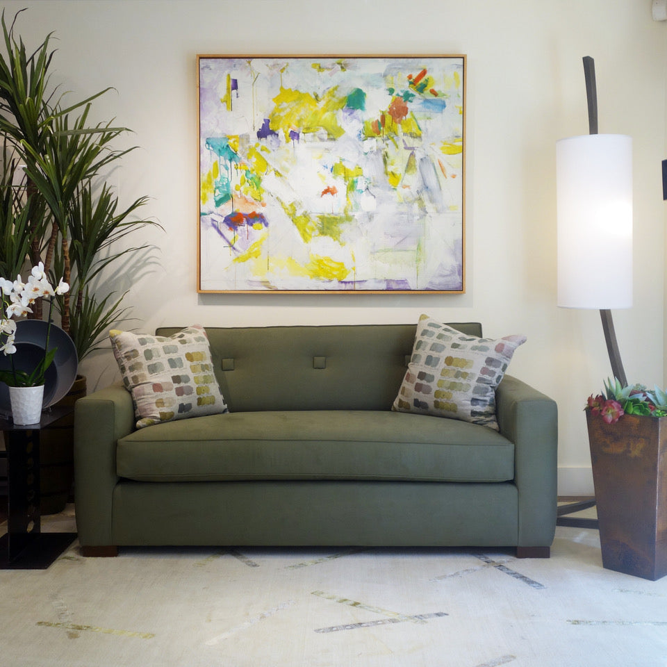 A custom designed sofa with an abstract art painting hanging above  on the wall, representing an extensive fine art collection.